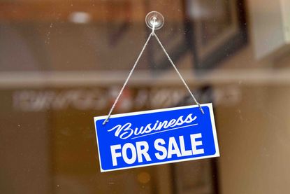 a business for sale sign hanging in a window