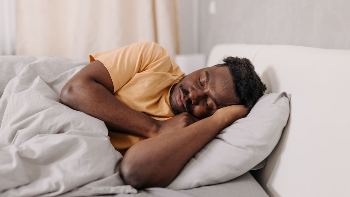 The image shows a man in bed sleeping deeply on his side