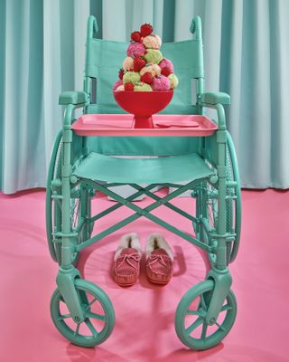 A bright green wheel chair against a pink background with ice cream on it