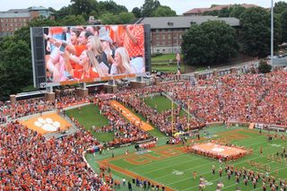 Clemson Tigers are ready to take the field and fans look on at a massive LED display in bright orange.