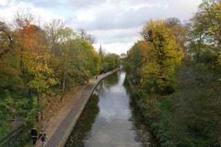 View from a high bridge over a tree lined canal in London