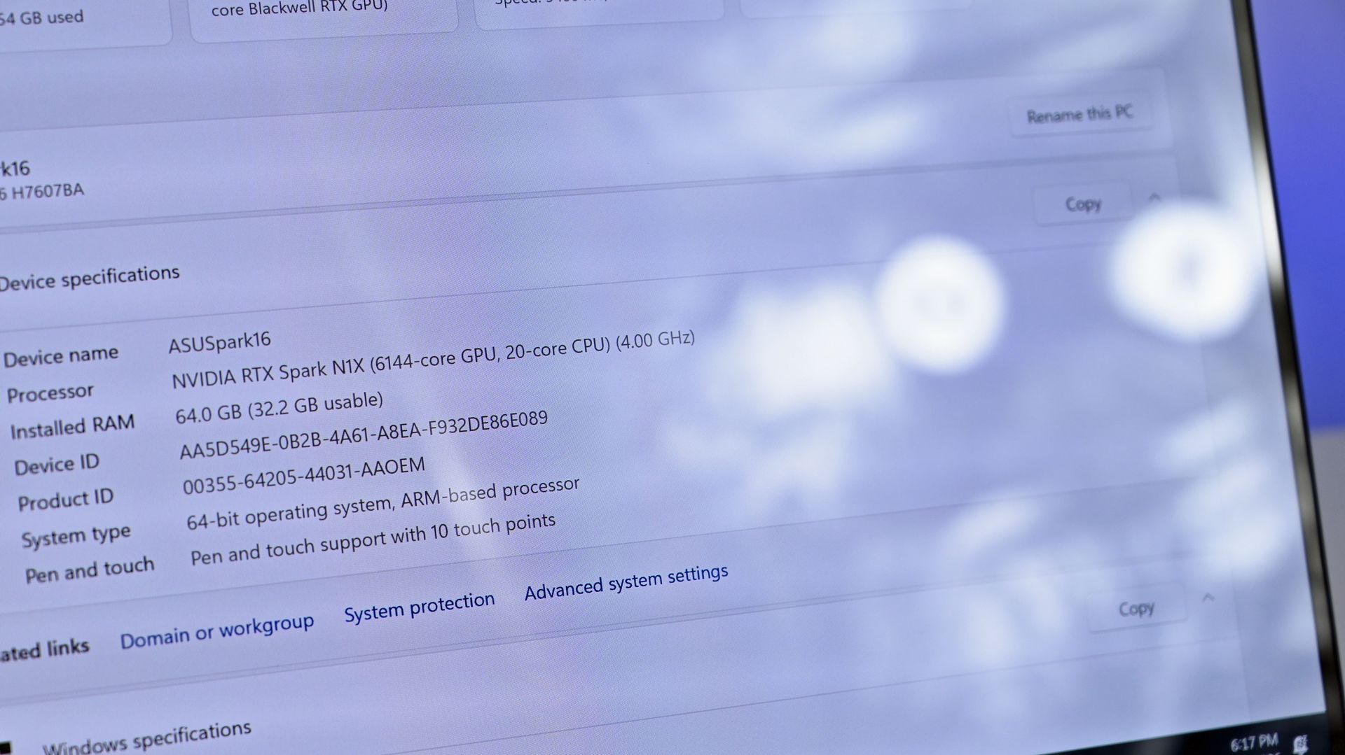 Close-up of the ASUS ProArt P16 glossy screen displaying Windows specs: NVIDIA RTX Spark N1X chip and 64 GB RAM, with noticeable circular light glare.