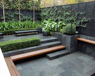 split level patio with dark paving and wooden built-in benches