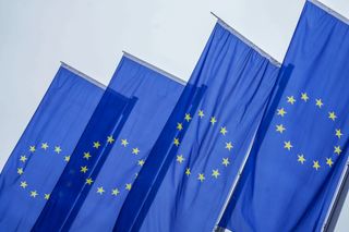 Flags of the European Union (EU) pictured on a still day with sunshine in background