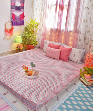 A colorful pink and blue bedroom with Indian patterns and motifs throughout