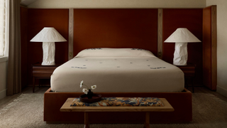 red bedroom with low bed and, a bench at the end, and paper bedside lamps