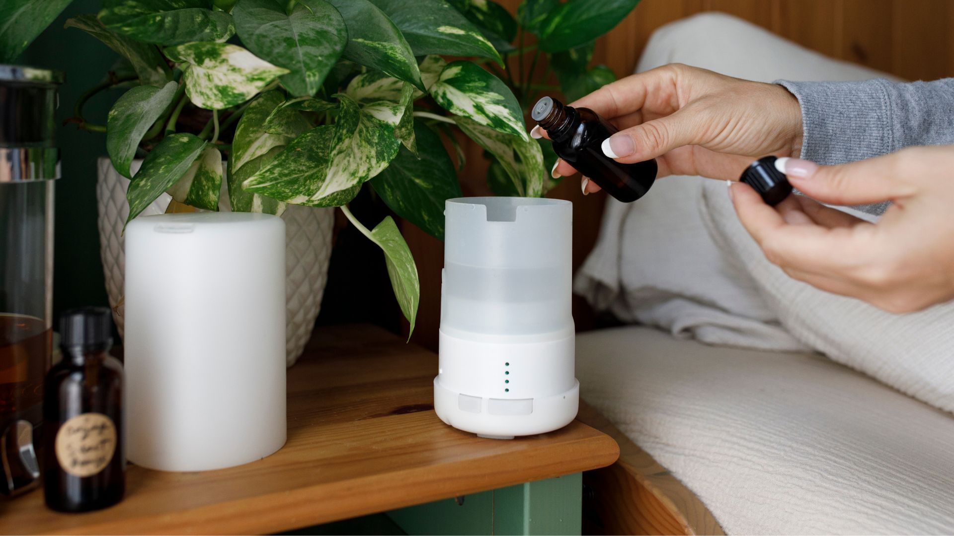 A woman's manicured hand fills a diffuser with lavender oil to relax her for better sleep.