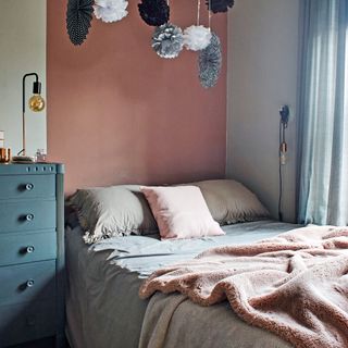 bed with pink and grey bedding in front of pink wall