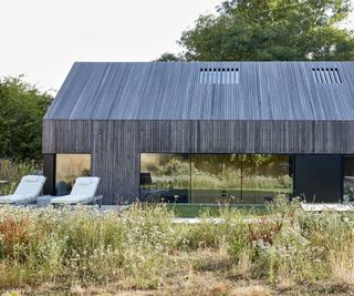 A dry gravel mediterranean style garden in front of a contemporary timber-clad self build