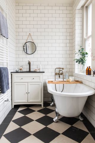 bathroom with a traditional roll top bath, monochrome tiles and white towel radiator