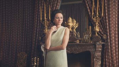 a woman (naomi watts as babe paley) stands in front of an ornate fireplace and candelabras