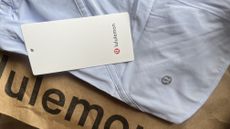 Item of white Lululemon clothing on brown paper bag with Lululemon written on it with Lululemon sale tag resting on top