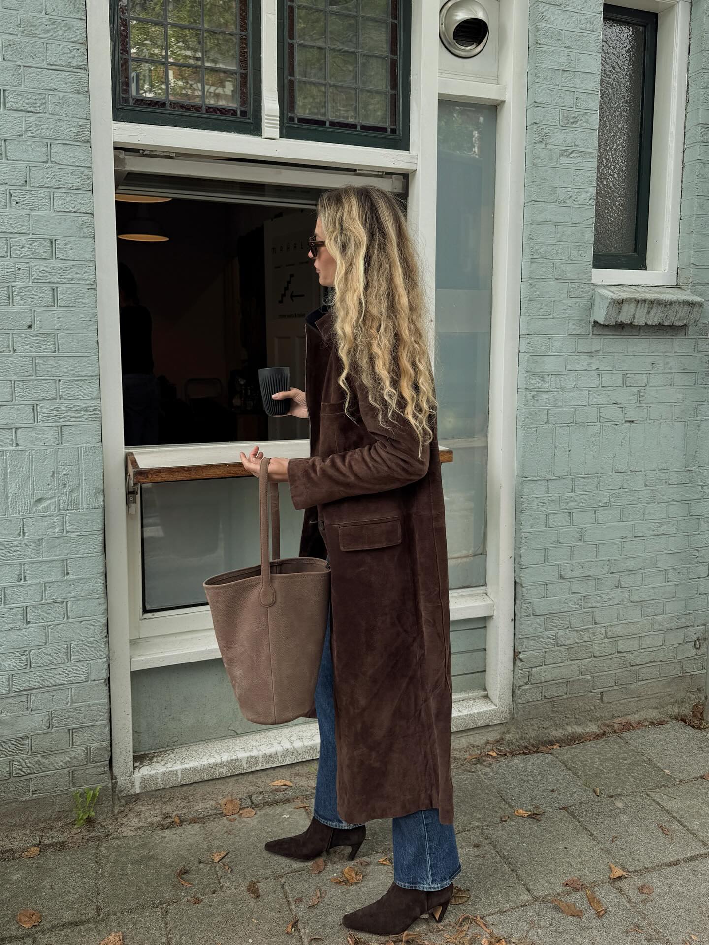 @anoukyve wears a suede jacket, blue ankle-length jeans and heeled boots.