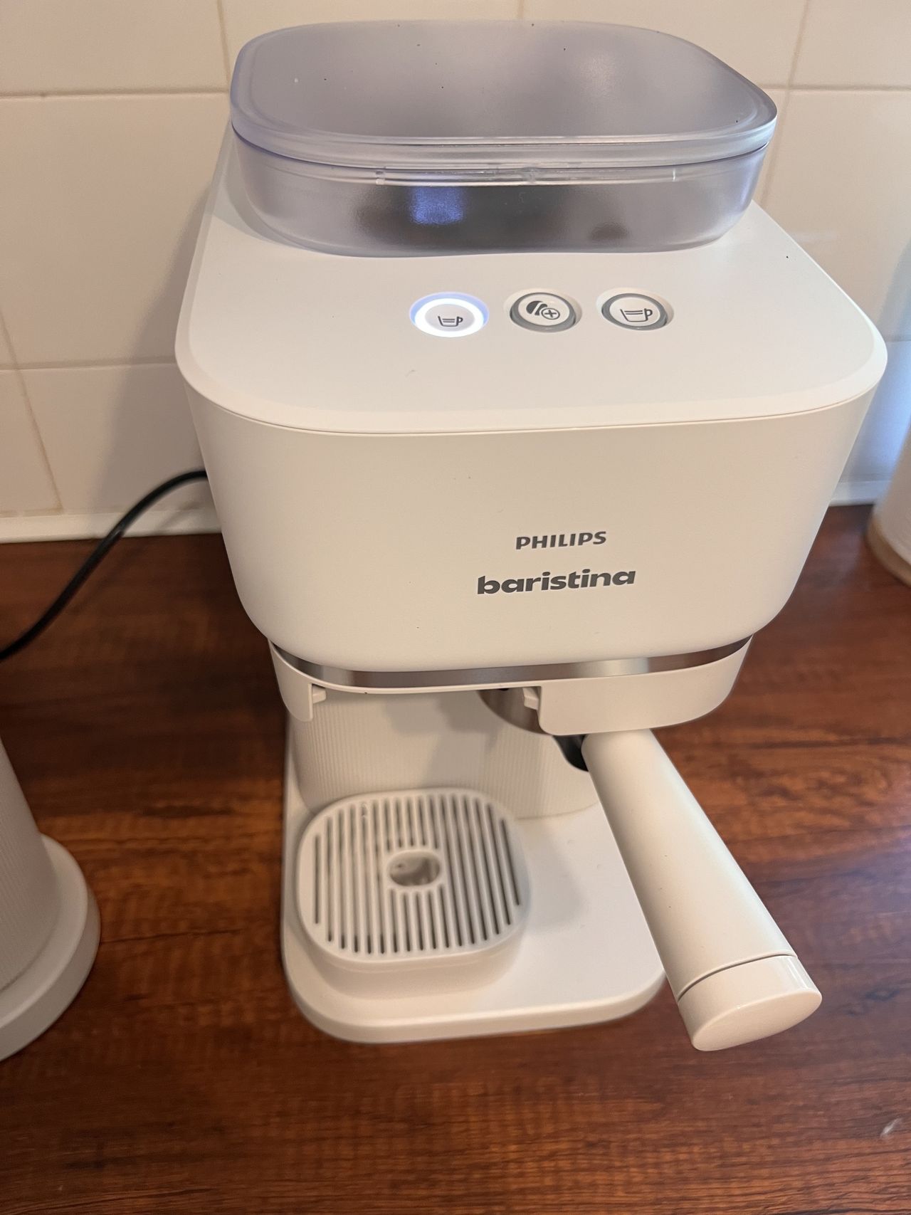 Image of a white Philips Baristina coffee machine on a wooden countertop.