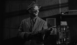 Sterling Hayden with a gun and wearing a clown mask