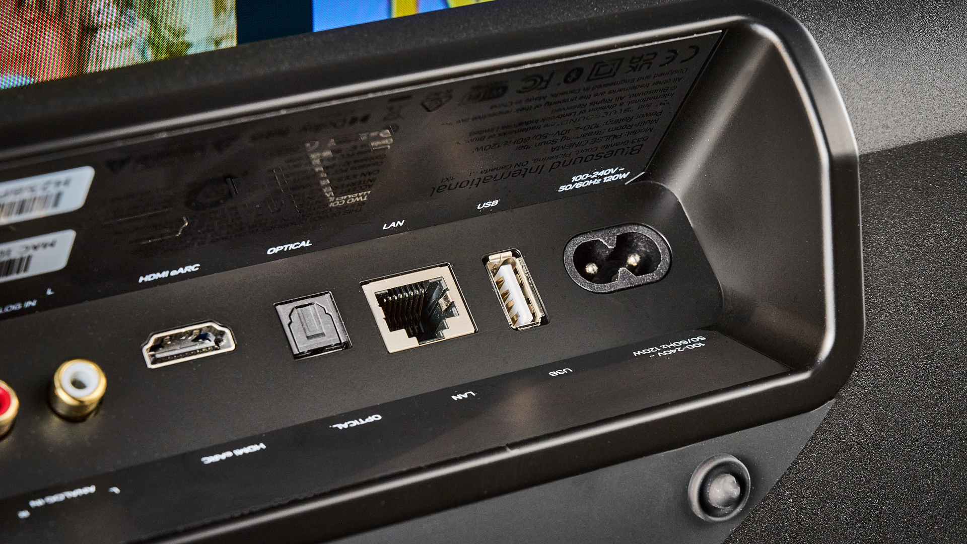 the bluesound pulse cinema soundbar photographed with a TV and the tom's guide blue background