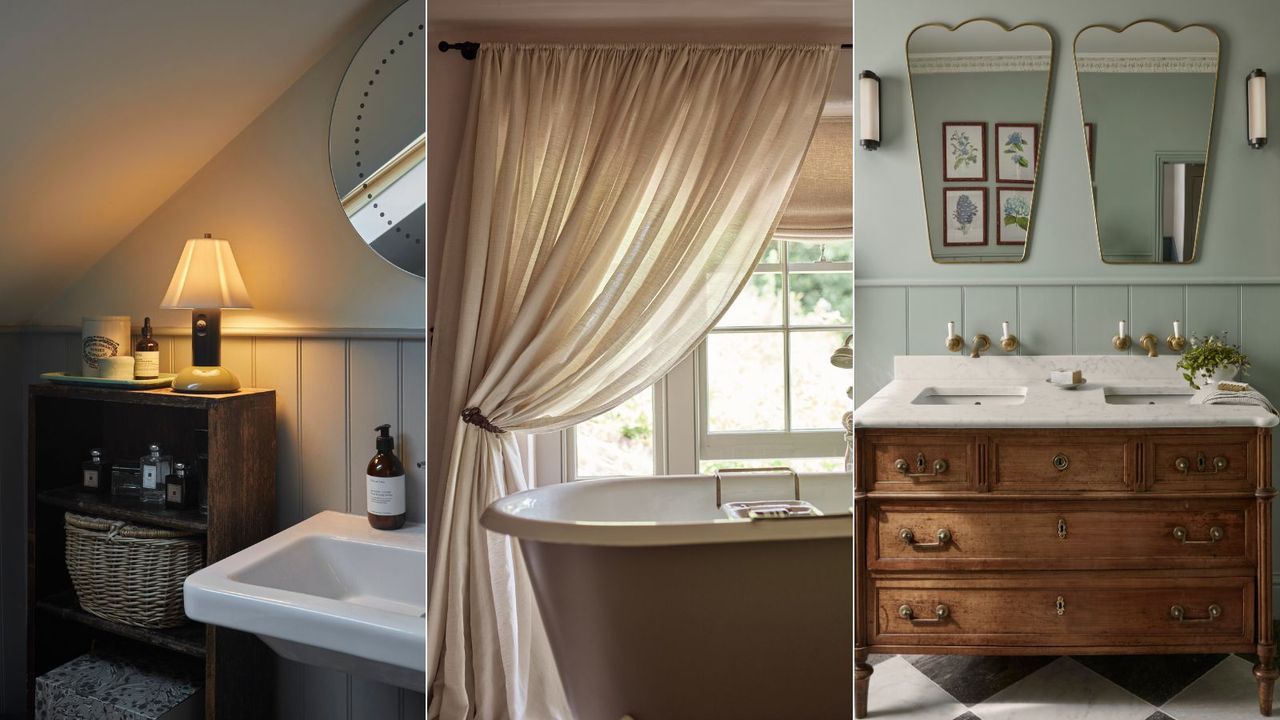 A standalone wooden shelving unit beside a sink with a lamp on top / A roll top bath in a window with a large curtain hanging beside it / A wooden bathroom drawer vanity with two sinks and matching mirrors