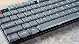 A black Keychron K13 Max wireless keyboard with gray and orange keycaps