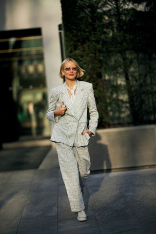 A woman at Milan Fashion Week's Fall 2025 Street Style in a gray plaid suit and white necktie