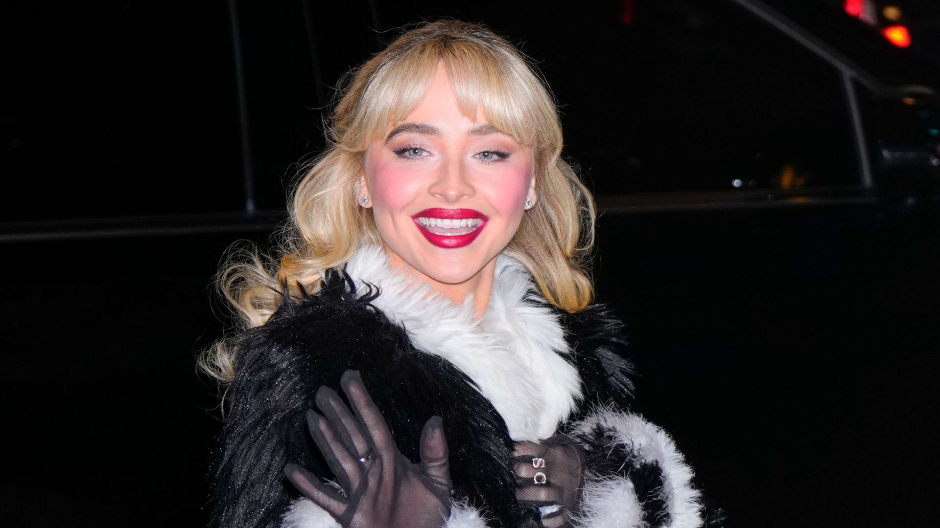 Sabrina Carpenter wearing red lipstick and a black and white fur coat