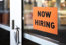 Orange "now hiring" sign in storefront window