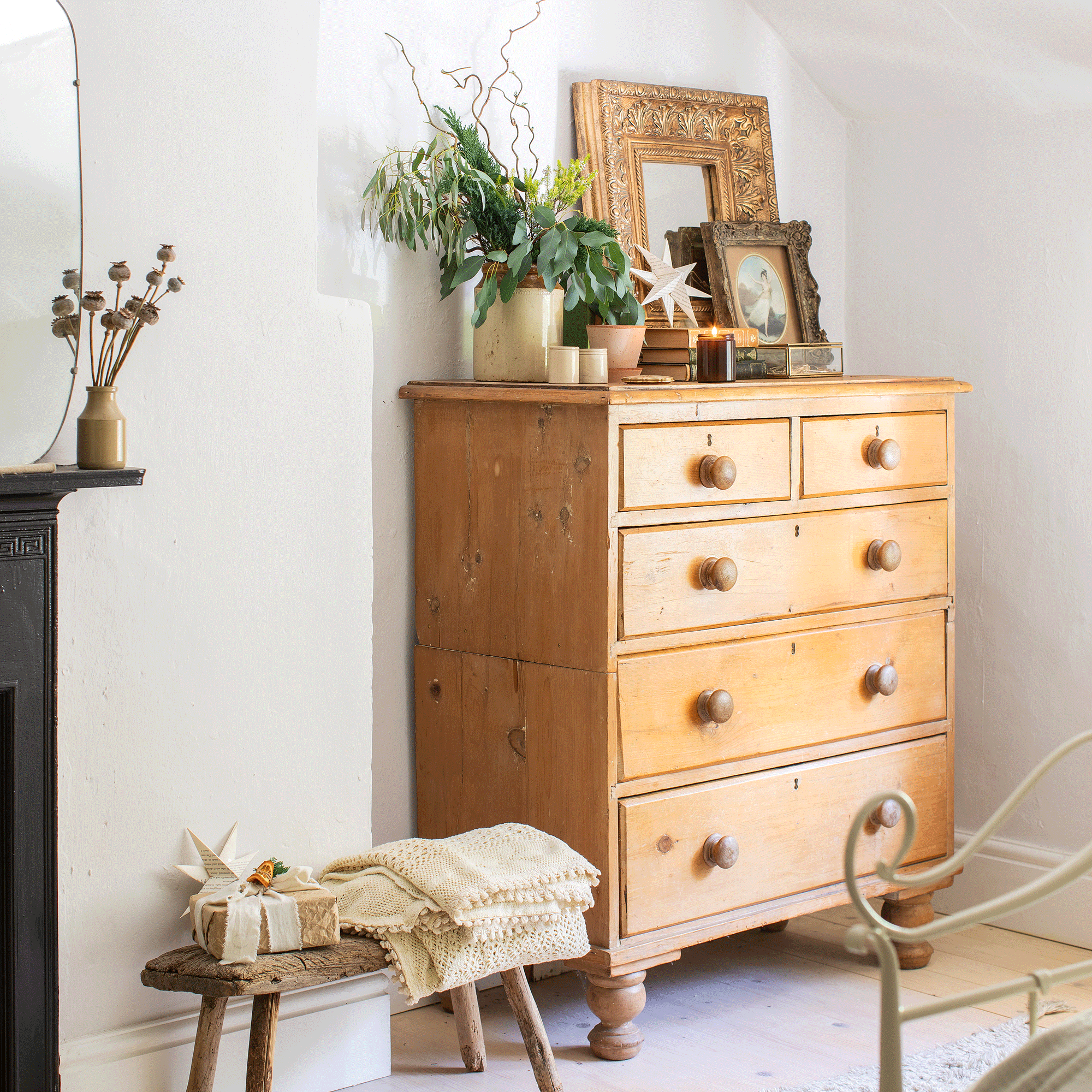 a chest of drawers in a bedroom beside a small rustic stool