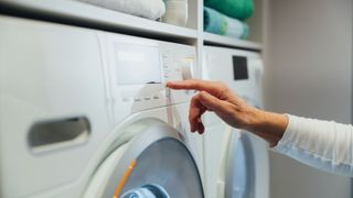 Hand choosing setting on tumble dryer