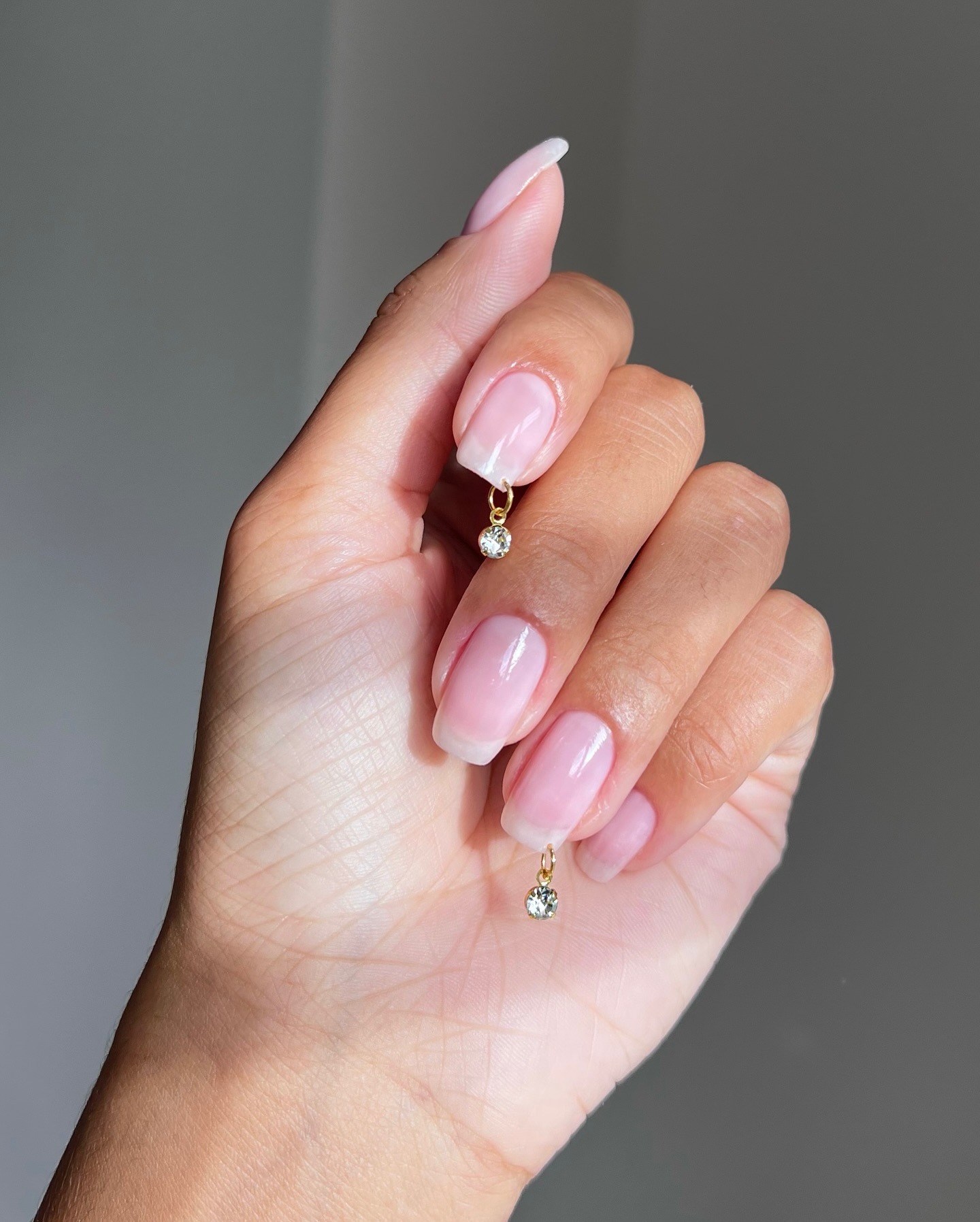A clear manicure with hanging gems