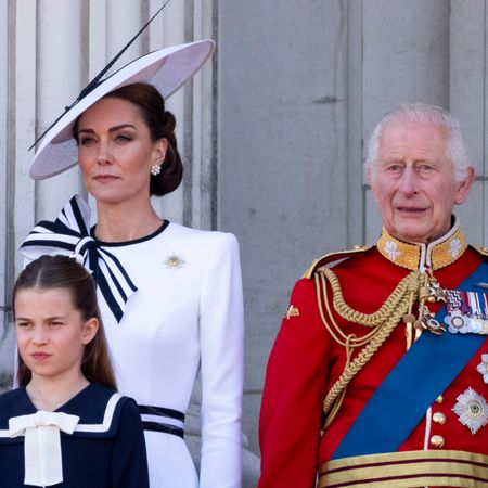 Kate Middleton wears a white dress with navy piping as she stands on the balcony with Prince William and King Charles, who wear military uniform