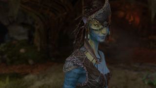 Still from the video game Avatar: Frontiers of Pandora. Close up from a Na'vi (tall, blue humanoid) from the Kame'tire clan. She has long black dreads and large yellow eyes. She is wearing some leather armor, and a sort of triangular leather headpiece. She has yellow paint on her face and neck. She has a very serious look on her face.