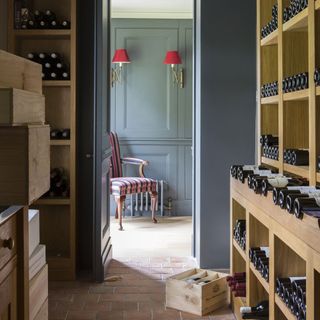 grey wall with wooden bottle shelves and armchair