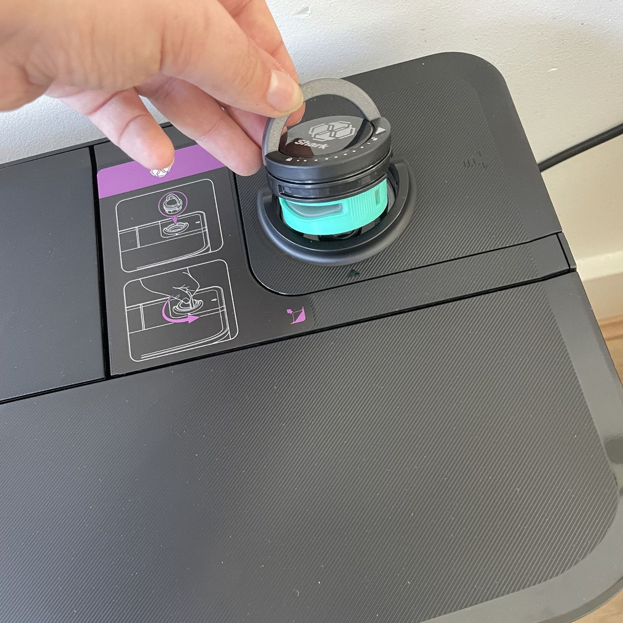 Hand inserting the anti-odour cartridge into the top of the Shark PowerDetect UV Reveal 2-in-1 Vac &amp; Mop Robot Vacuum