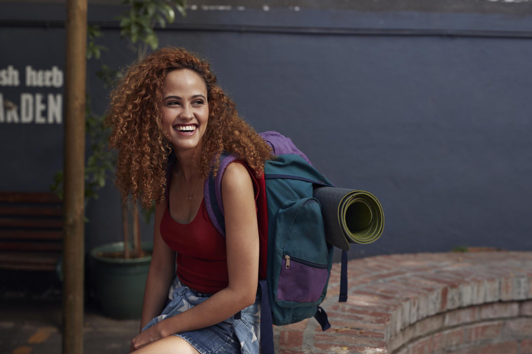  Smiling female student traveller with a travellers rucksack on 