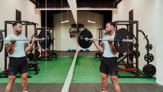Man performs barbell curl, checks his form in the mirror