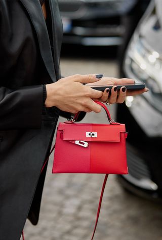 a street-style photo of a woman carrying a Hermés bag in a story about how to buy an hermés bag