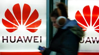 A shot of a woman walking in front of a Huawei sign