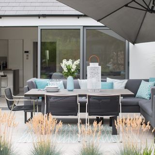 Grey and white modern garden dining set with teal cushions on a patio with light grey paving stones