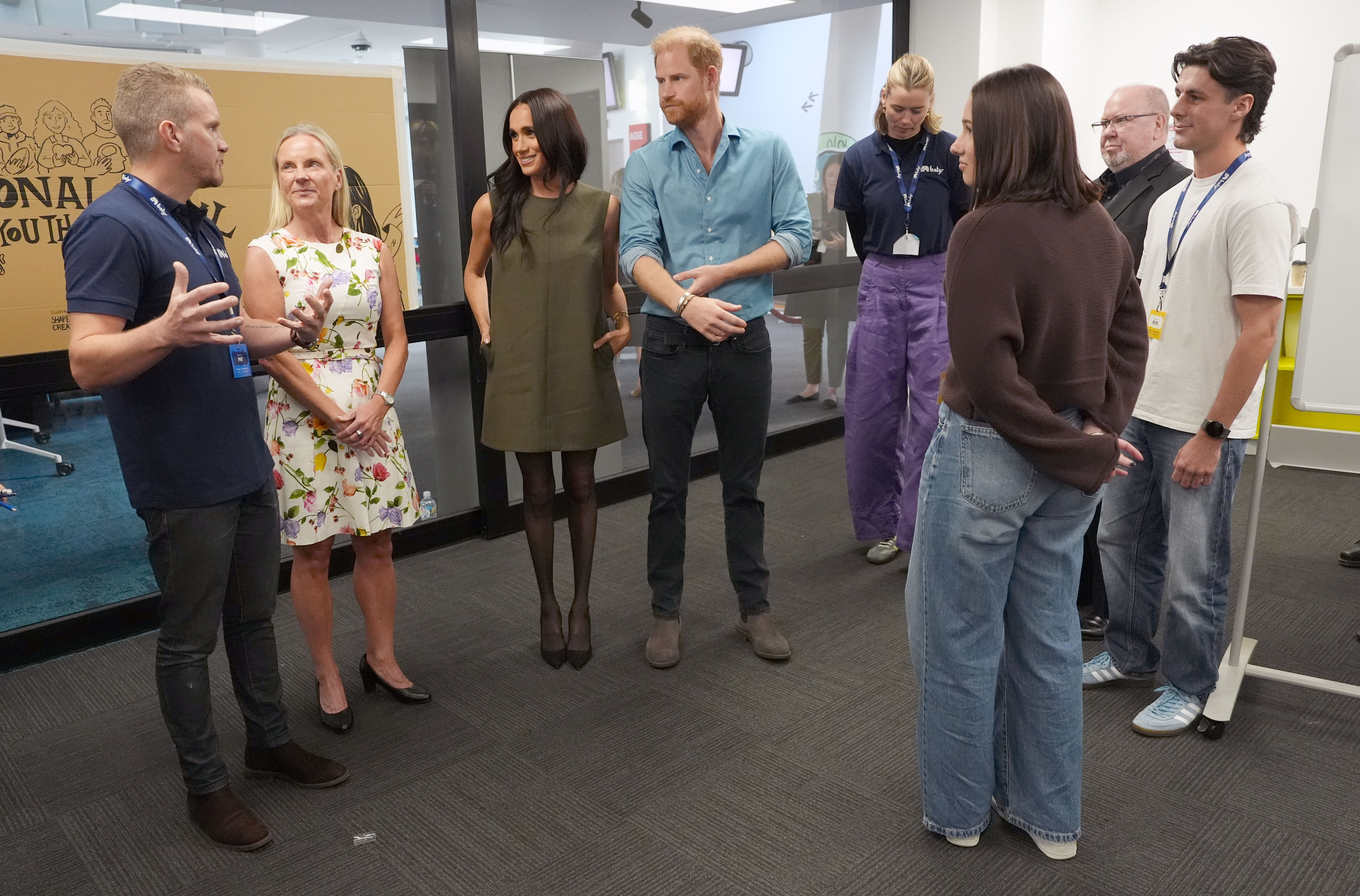 Meghan Markle and Prince Harry standing and speaking to a group of people at a mental health program