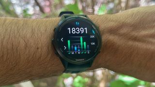 The Garmin Forerunner 970 worn on a wrist showing a step count widget for the past week, highlighting 18,391 steps tracked on Thursday. 