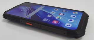 An angled, close-up shot of the AGM G3 Pro resting on a white surface, showcasing its ruggedized chassis and the active home screen display