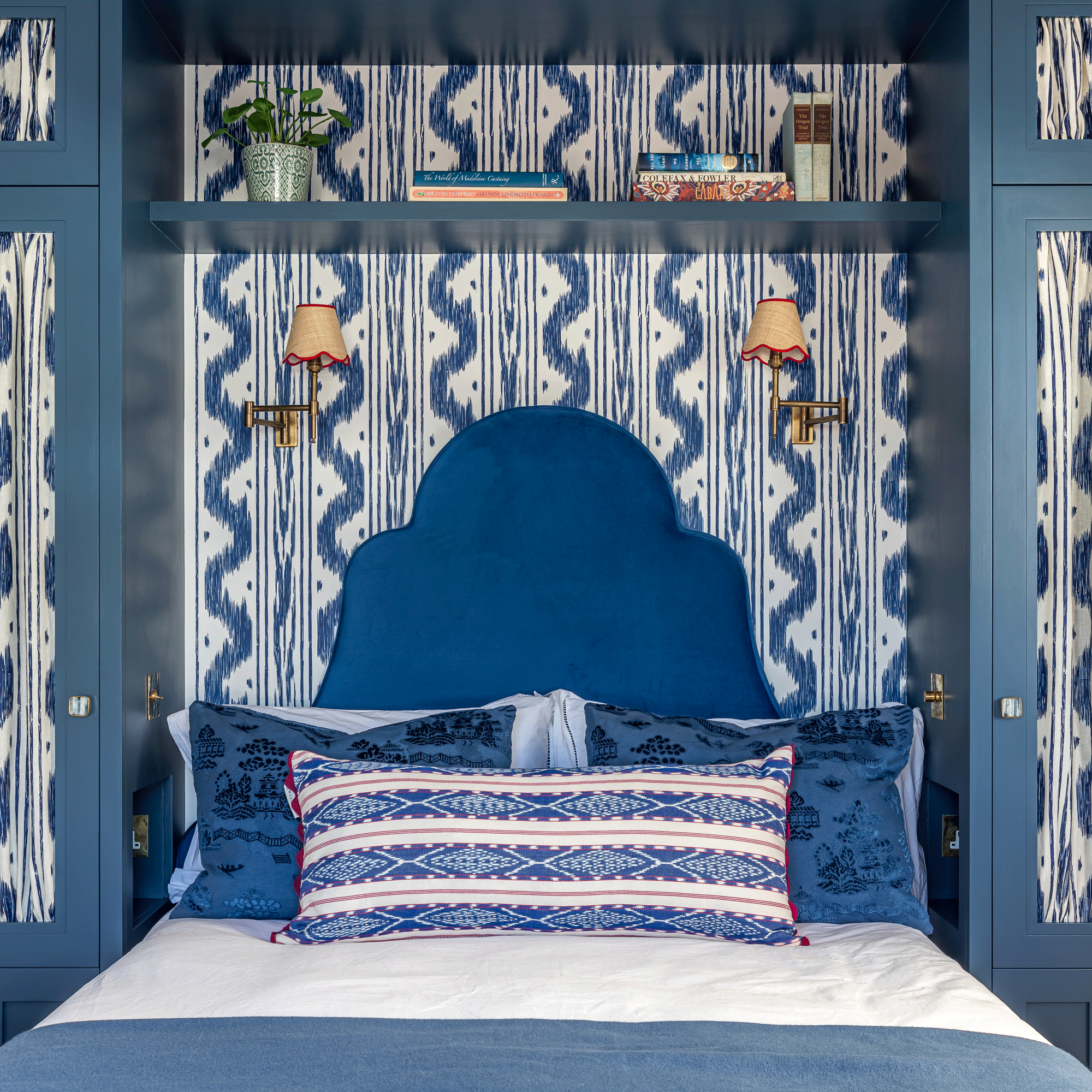 Bedroom with navy blue headboard and patterned wallpaper