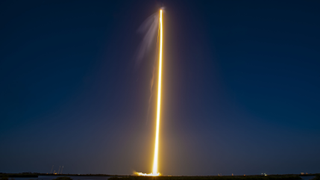 yellow streak of a rocket lifting off against a dark sky