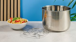 a black instant pot with a dial and touchpad is photographed against a blue background