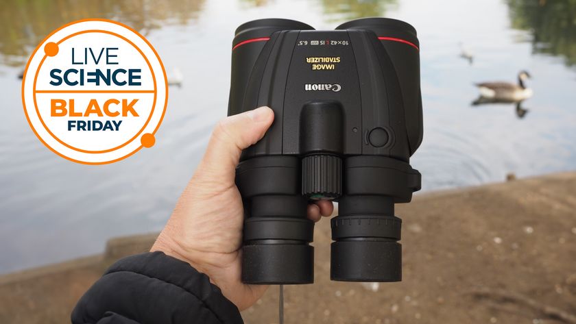 canon 10x42L IS WP in the hands of the reviewer infront of a lake