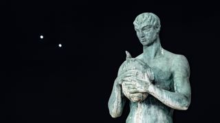 Venus and Jupiter appear very close in the night sky with a statue in the foreground