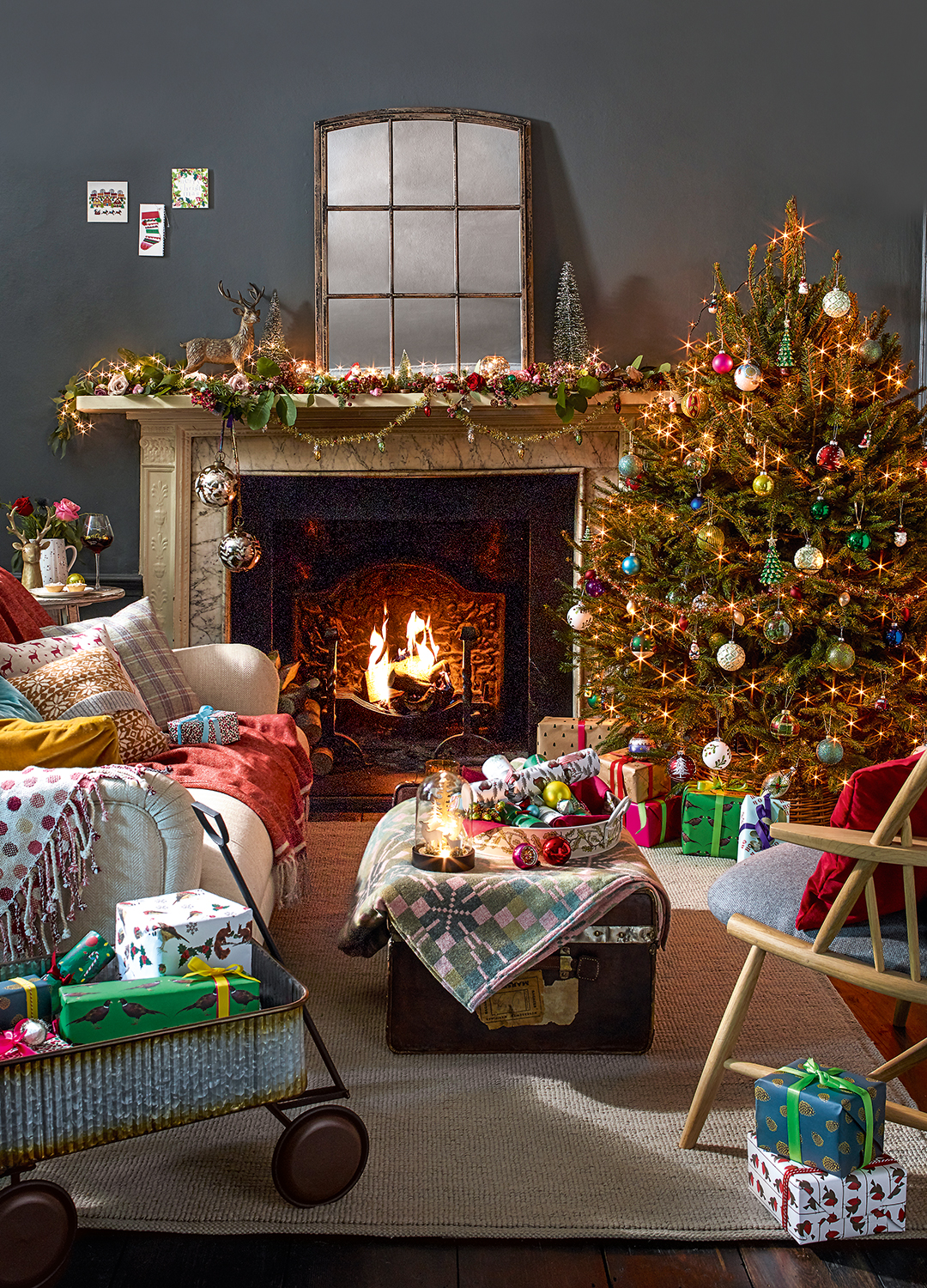 Living room decorated for Christmas with a brightly coloured tree and mantlepiece display