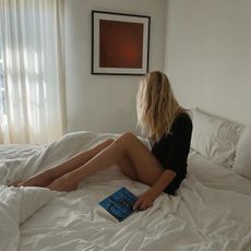 Woman laying in bed with a book