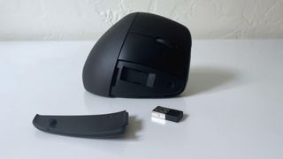 The HP 925 ergonomic vertical mouse with dongle housing open on a white desk