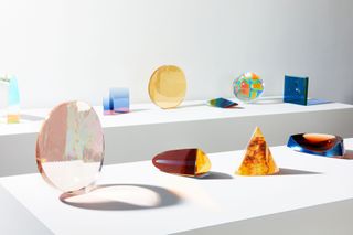 Colourful glass objects on white plinths