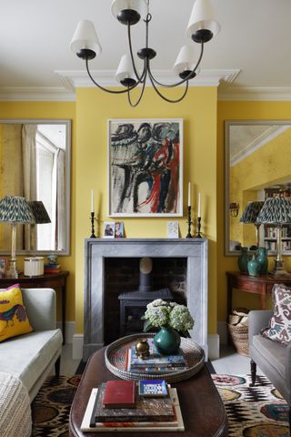 Yellow living room with marble fireplace and large mirrors in alcoves